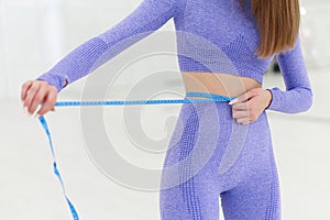 Woman in trendy colour sportswear holding tape measure