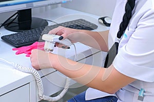 Woman trichologist adjusting trichoscope testing it on her hand, closeup view.