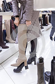 A woman tries on boots in a shoe store. Fashion, style and beauty. Vertical