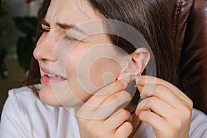 A woman tries to put an earring in her ear, earlobe problem, the hole is overgrown