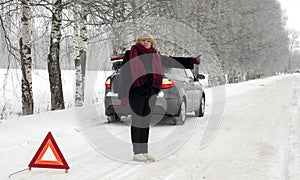 A woman tries to stop a car on a winter road. Sign on an emergency stop.