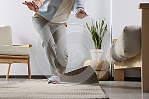 Woman tripping over carpet at home, closeup