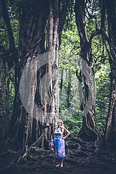 Woman on the tropical balinese landscape background, North of Bali island, Indonesia. Standing near Ficus tree.