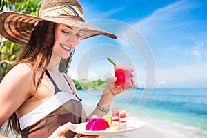 Woman at tropical beach eating fruit for breakfast