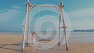 Woman on tropical summer vacation swinging on wooden swing