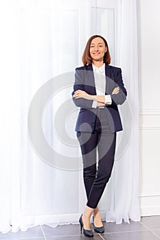 Woman in trouser suit standing with arms crossed