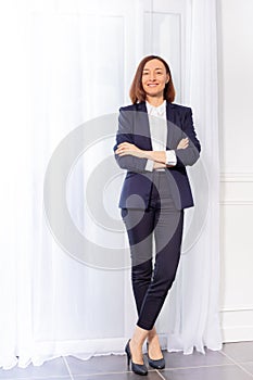 Woman in trouser suit standing with arms crossed photo