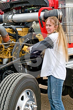 Woman truck driver checking the oil level on a big truck