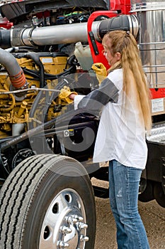 Woman truck driver checking the oil level on a big truck