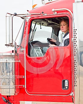 Woman Truck Driver looking out the window while driving a big rig