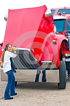 Woman truck driver pulling the hood to check engine fluids