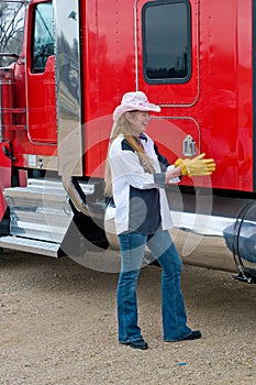 Woman Truck Driver putting on her gloves to inspect a big rig