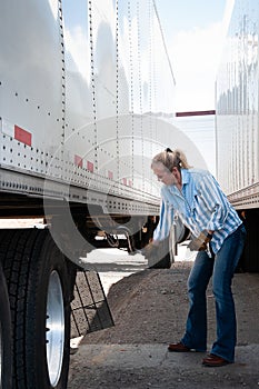 Woman truck driver raising the landing gear on a trailer