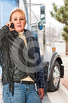 Woman truck driver talking on the cell phone to her dispatcher.