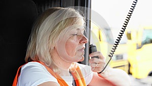 Woman truck driver talking by radio inside the cabin. Female trucker job worker