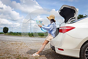 woman in the trunk of a car looking at a map to reach the holiday destination with blue sky