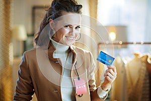 Woman trying coat with sale price tag and holding credit card