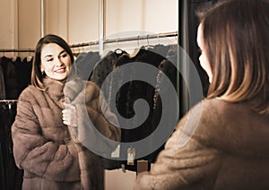 Woman trying on fur coat in womenâ€™s cloths store