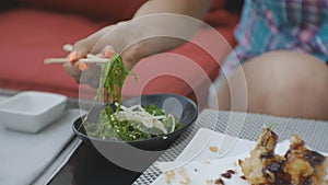 Woman trying japanese cuisine. Close-up of attractive young caucasian woman biting seaweed salad taking it with