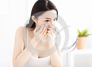 woman trying to apply contact lenses in front of mirror