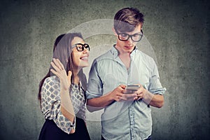 Woman trying to bring attention of a handsome man ignoring her using a smartphone