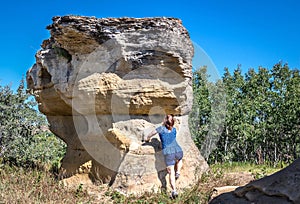 Woman trying to climb up a natural sandstone rock formation.