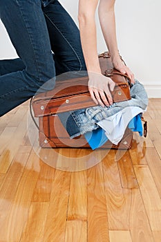 Woman trying to close overfilled suitcase