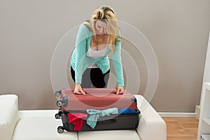 Woman trying to close the suitcase