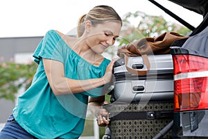 woman trying to fit suitcases in car