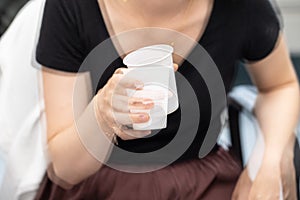 Woman trying to hold a drink with severe and involuntary body tremor