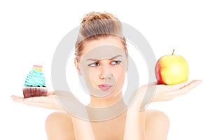 Woman trying to make a decision between cupcake and apple