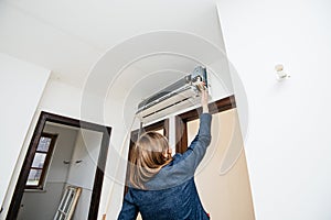 Woman trying to repair newly installed air conditioner wall ac unit