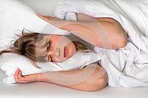 Woman trying to sleep, she covering ears with pillow