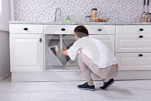 Woman Trying To Stop Water Leakage From Sink Pipe