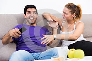 Woman trying to take away TV remote from boyfriend