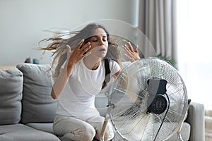 Woman turned on fan waving her hands to cool herself