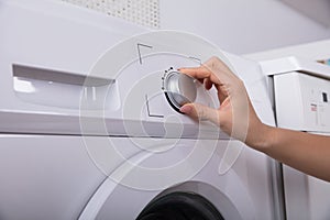 Woman Turning Button Of Washing Machine