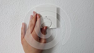 Woman turning down heating thermostat to save money. Female turn off heating. Central Heating thermostat control dial