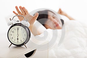 Woman turning off the alarm clock on the bed