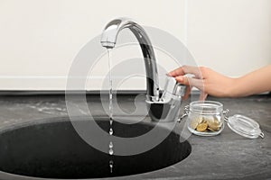 Woman turning off tap in bathroom. Water saving concept