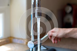 Woman turning on a tap with running water