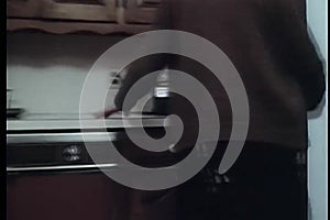 Woman turning on transistor radio on kitchen counter