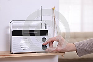 Woman turning volume knob on radio at home, closeup