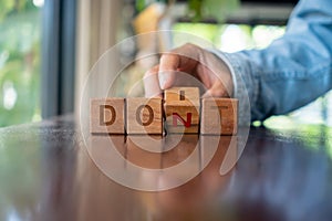 Woman turns a wooden cube with the words do it or don`t as a metaphor for making a decision