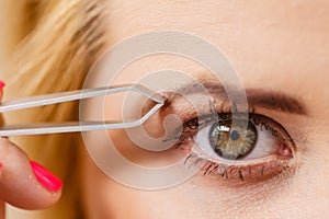 Woman tweezing eyebrows depilating with tweezers