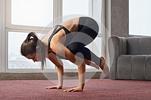 Woman twisting body at crow pose during training.