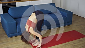 Woman twisting her arms, practicing yoga at home