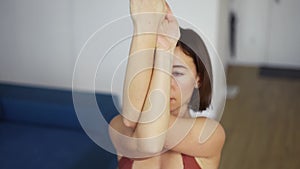 Woman twisting her arms, practicing yoga at home, close up