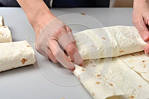 Woman twists ready-made shawarma into pita bread