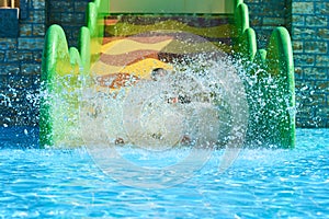 Woman and two boys on a water park slides. Happy family ride on water slides with flowing splash in aqua park